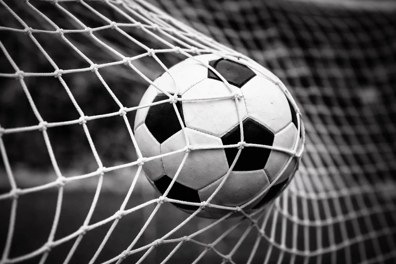 Fußballtor mit Tornetz und Ball im Stadion bei Flutlicht